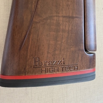 Peça de madeira castanha com gravação Perazzi HIGH TECH e faixa preta e vermelha