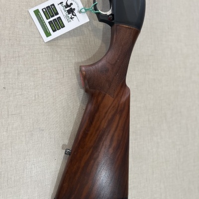 Espingarda com coronha em madeira castanha e punho texturizado, etiqueta pendurada