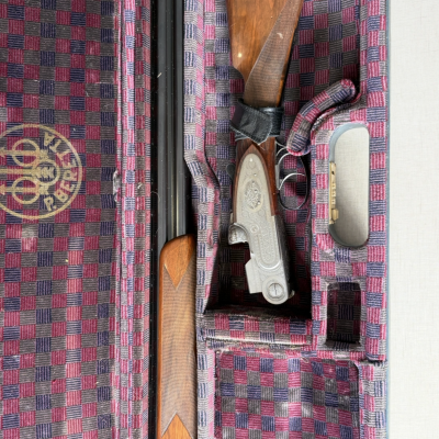 Espingarda de caça dentro de estojo com revestimento xadrez vermelho e azul, logótipo BERETTA visível