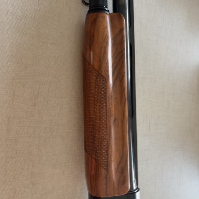 Espingarda com punho em madeira e acabamento preto com texto Benelli Armi