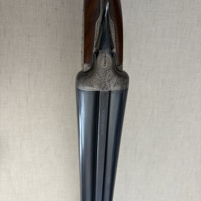 Escopeta dupla madeira e metal azul com detalhes gravados.