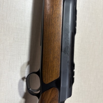 Carabina com partes em madeira e metal preto com texto SAUER 303