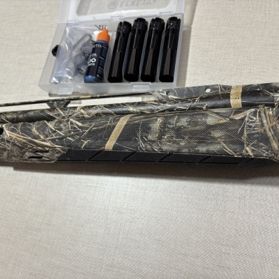 Espingarda camuflada com acessórios e frasco de óleo em estojo transparente