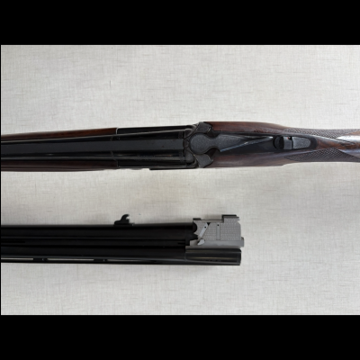 Espingarda de canos duplos desmontada em peças, em madeira escura e metal preto