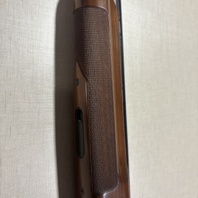 Espingarda de madeira castanha com textura quadriculada e detalhe metálico