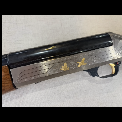 Espingarda com cabo em madeira e armação metálica decorada com pássaros dourados, cano preto e gatilho dourado.