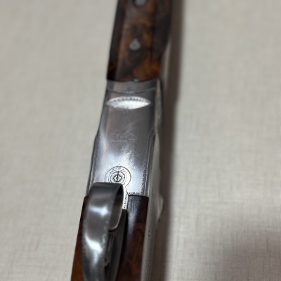 Arma de fogo com punho em madeira castanha e detalhes em metal gravado