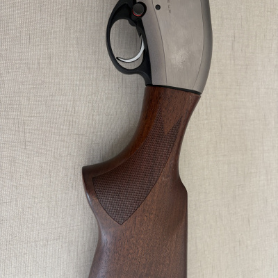 Ponteira e gatilho de arma de fogo com madeira castanha e metal prateado com texto.