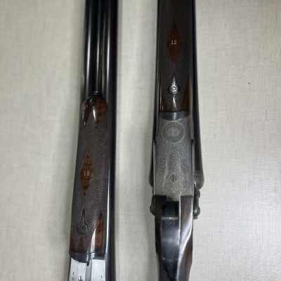 Duas armas de canos duplos com punhos de madeira e marcas numéricas