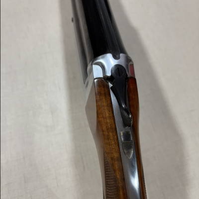 Espingarda dupla calibre 12 com canos pretos e coronha em madeira castanha com textura entalhada