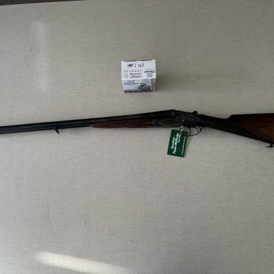 Espingarda de cano duplo com coronha de madeira escura e acabamento em borracha vermelha