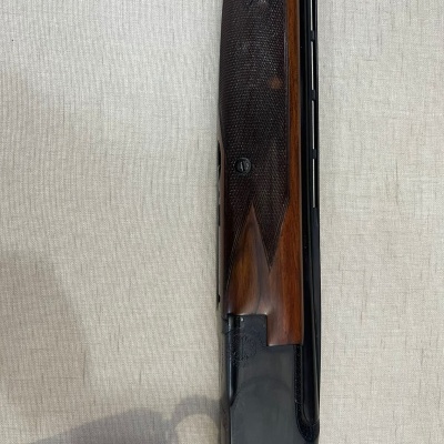 Espingarda com coronha de madeira castanha e cano preto sobre fundo claro