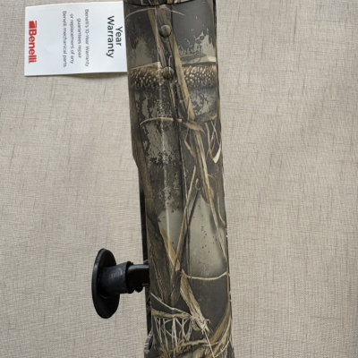 Arma de fogo camuflada com etiqueta de garantia Benelli sobre fundo cinzento claro