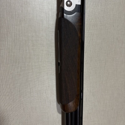 Parte superior de uma espingarda com punho em madeira castanha e corpo metálico prateado