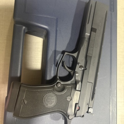 Pistola Beretta preta sobre caixa azul escura