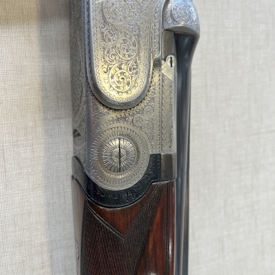 Espingarda com coronha em madeira e metal gravado em fundo bege