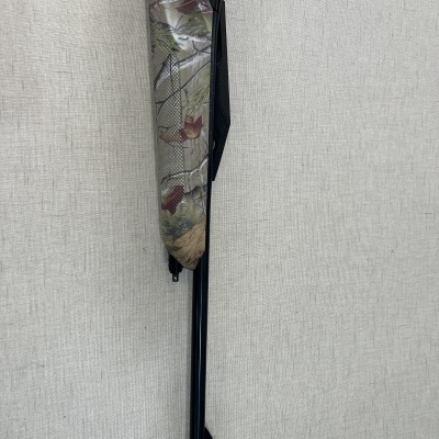 arma de ar comprimido com coronha decorativa e cano preto encostada numa parede cinza