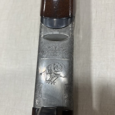 Arma de fogo com parte metálica gravada e madeira castanha