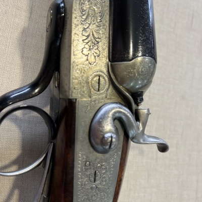 Espingarda dupla de metal gravado e madeira escura com gatilhos expostos