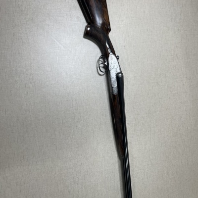 Espingarda de canos duplos com madeira escura e detalhes metálicos