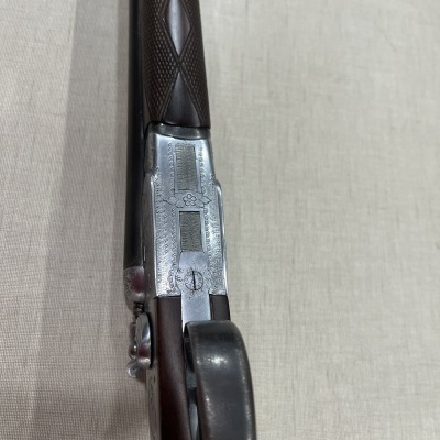 Espingarda de cano duplo com cabo em madeira escura e detalhes metálicos