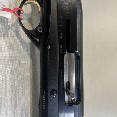 Parte de uma espingarda preta com punho castanho e inscrições gravadas.