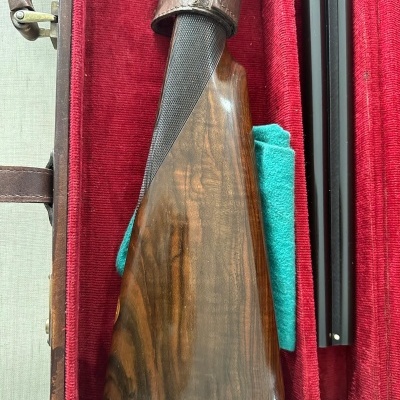 Estojo vermelho com arma de cano duplo e coronha de madeira escura