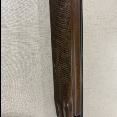 Parte de uma arma de fogo com coronha em madeira castanha trabalhada