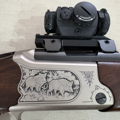 Parte lateral de carabina com gravação de animais na parte metálica e visor óptico