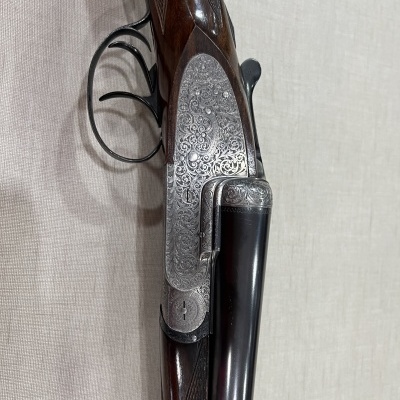 Espingarda de canos duplos com gravações ornamentais na parte metálica e madeira escura trabalhada