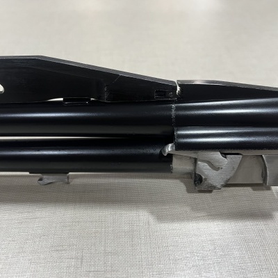 Parte metálica preta de mecanismo sobre fundo branco texturado