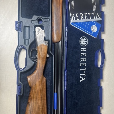 Arma de caça Beretta desmontada num estojo azul com manuais.