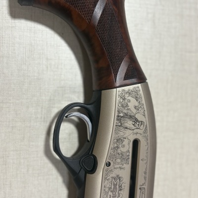 Espingarda com guarda-mão em madeira castanha e detalhes metálicos gravados.