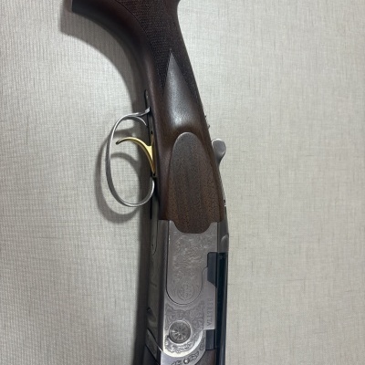 Espingarda Beretta com madeira escura e detalhes metálicos gravados