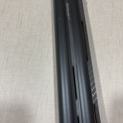 Peça metálica preta com texto STEELIUM PRO e detalhe em fibra de carbono