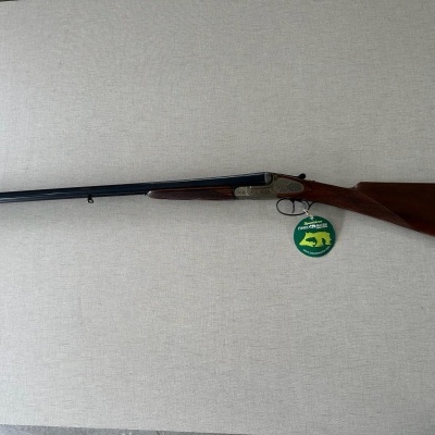 Espingarda de canos duplos com coronha em madeira e etiqueta verde pendurada
