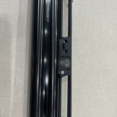 Régua de alumínio preta com texto e botão deslizante sobre tecido claro