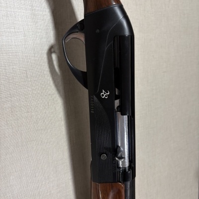 Espingarda de caça com corpo metálico preto e cabo em madeira castanha