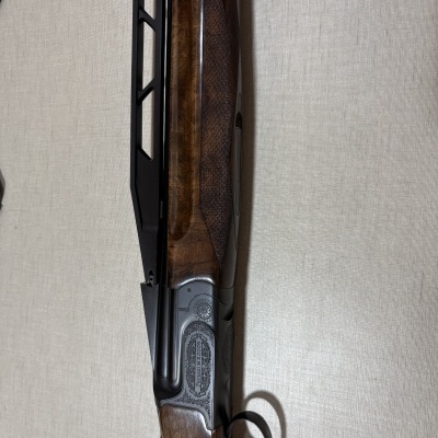 Espingarda de caça madeira polida e metal gravado com gatilho dourado.