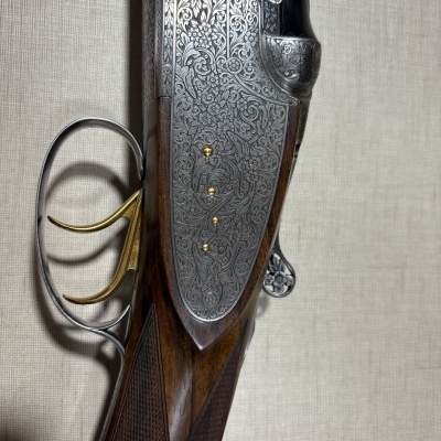 Espingarda com detalhes em metal gravado e madeira escura com disparadores dourados