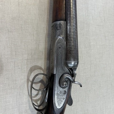 Espingarda de dois canos com madeira escura e detalhes em metal grabado