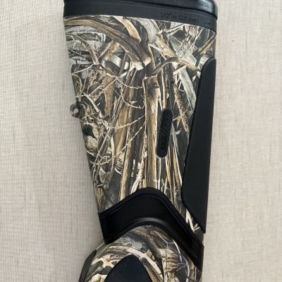 Parte superior de bota camuflada com detalhe preto e texto gravado.