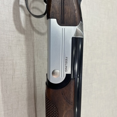 Espingarda com madeira escura e metal prateado com a palavra FEELING