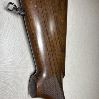 Coronha da espingarda em madeira castanha com textura antiderrapante e suporte metálico para correia