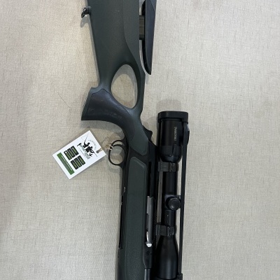 Espingarda com coronha preta e luneta sobre superfície cinza clara