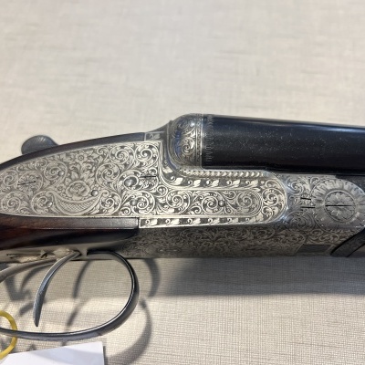 Espingarda de canos duplos com corpo em metal gravado e coronha em madeira escura