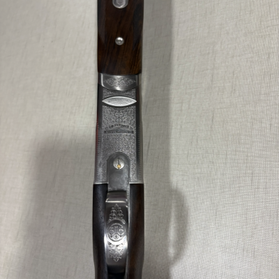 Espingarda em madeira escura e metal prateado gravado com inscrições 'MADE IN ITALY'