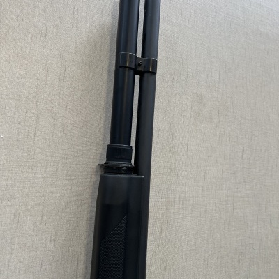 Arma de fogo com cano duplo preto e coronha preta apoiada numa superfície clara