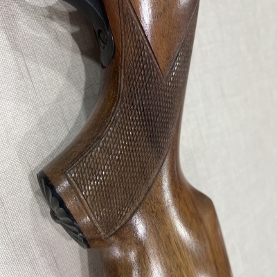 Empunhadura de madeira castanha polida com textura quadriculada e parte metálica preta