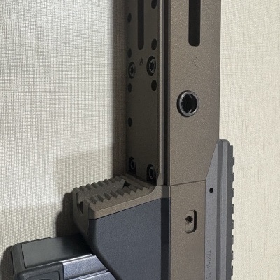 Estrutura metálica cinza e preta com parafusos e furos junto a uma parede clara